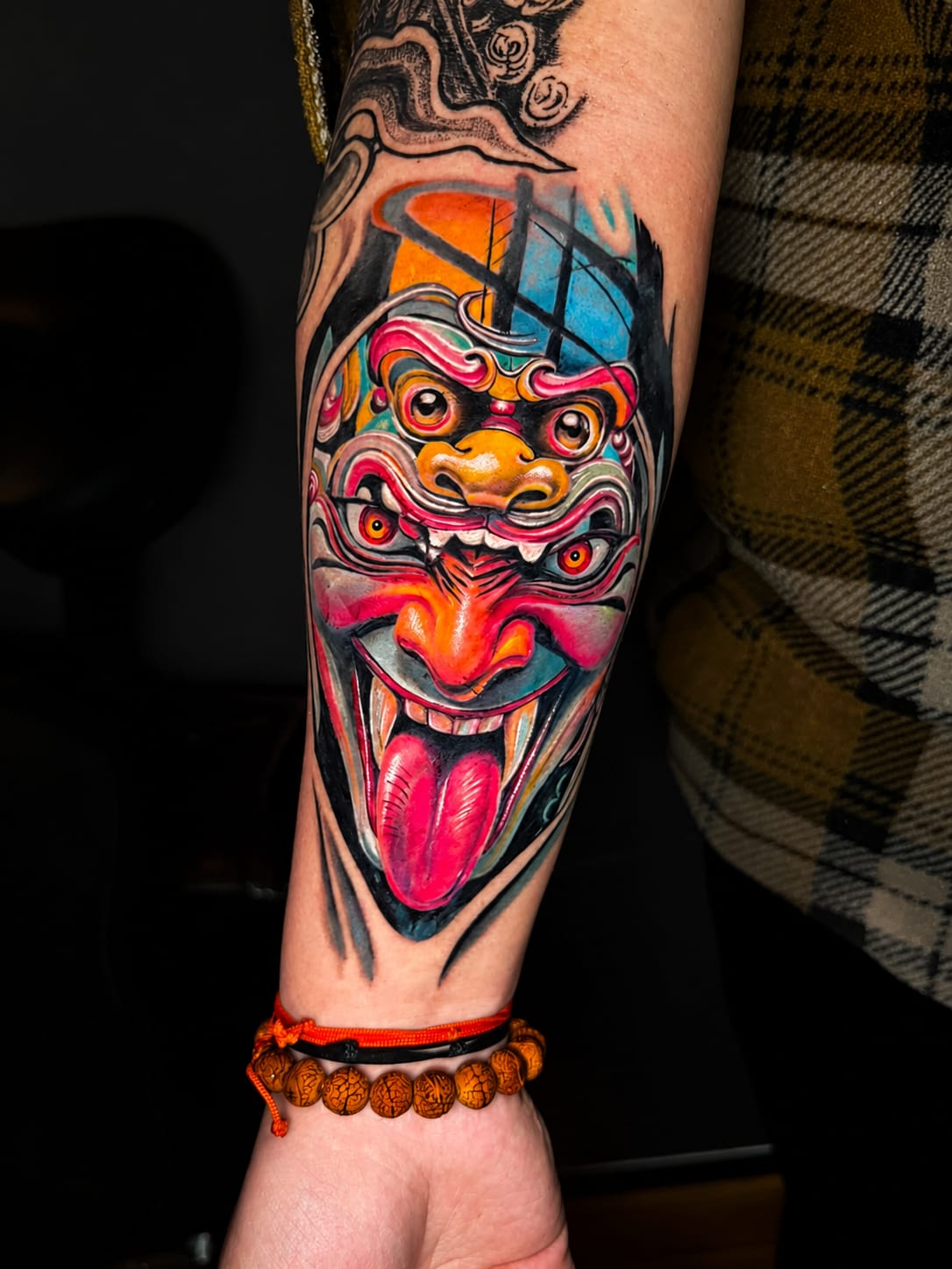 Vibrant neo-traditional Barong mask forearm tattoo in full colour, Dev Tattoo & Art Kolkata